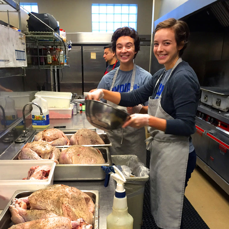 Student volunteers cook in a community kitchen.