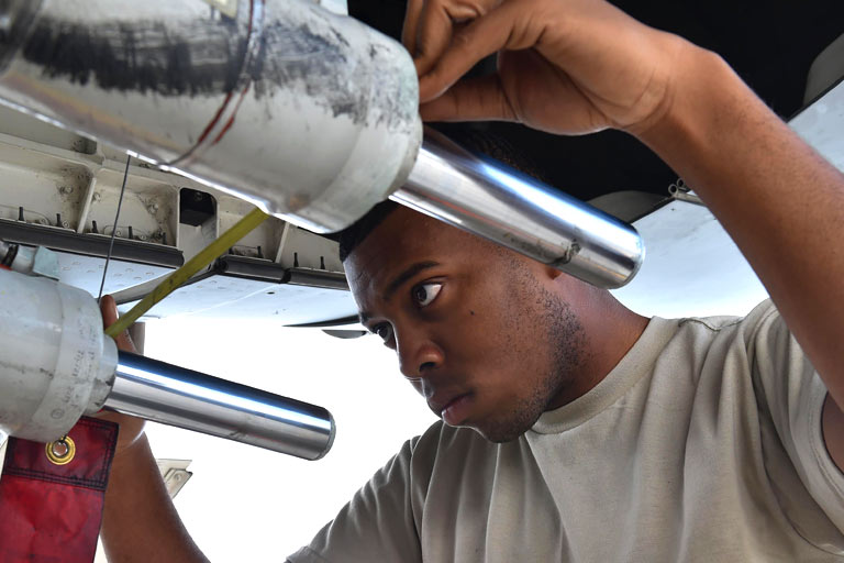 A young Air Force mechanic works on the engine of a plane.