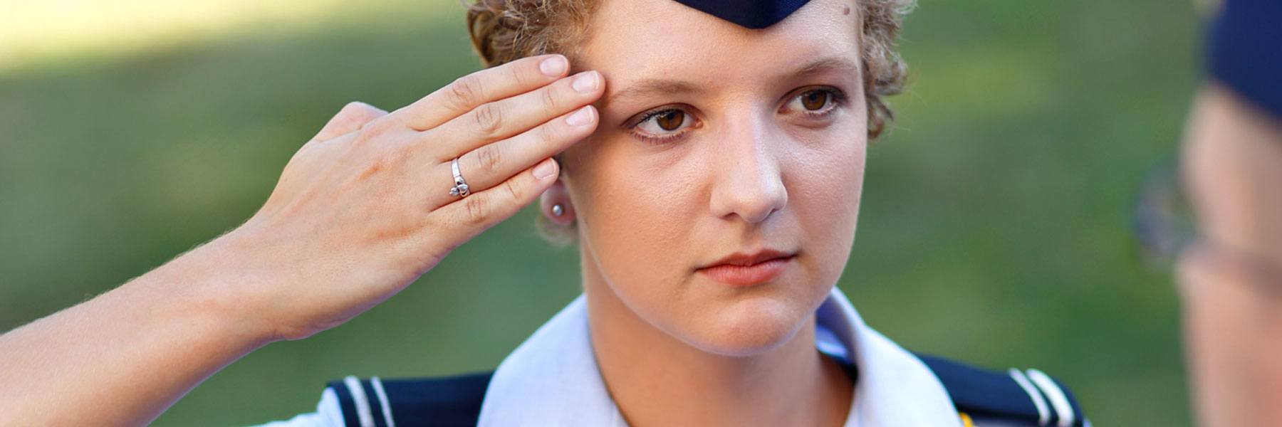 Female cadet wearing Air Force blues salutes a cadre member.