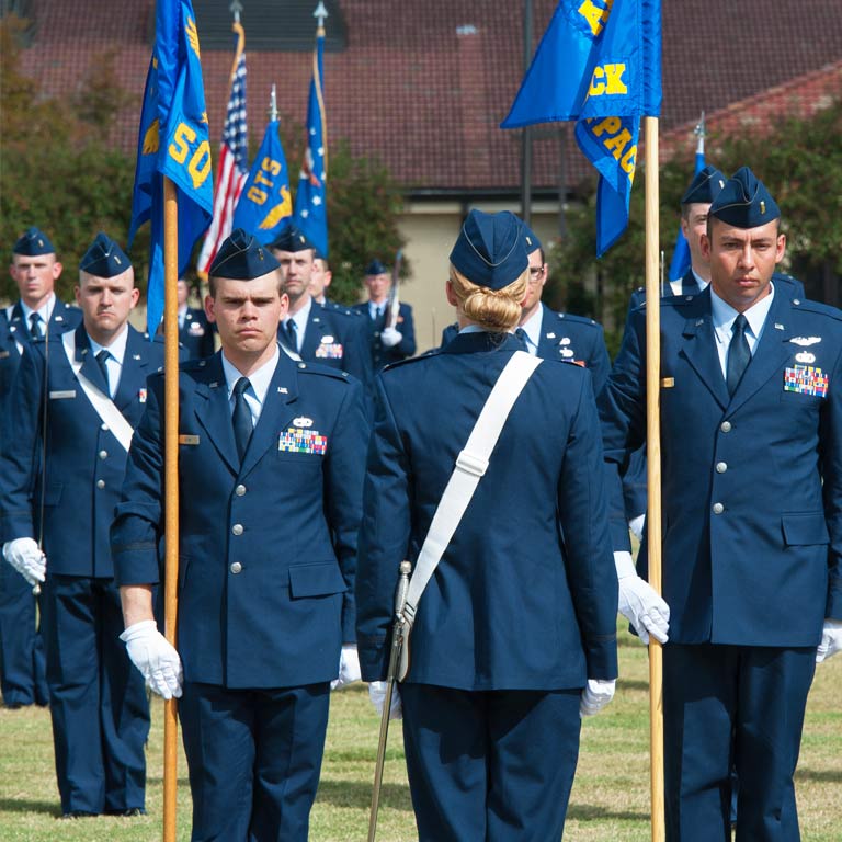 A female officer leads a group of uniformed airmen.